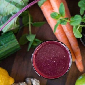 a glass of fresh pressed juice with vegetables in the background