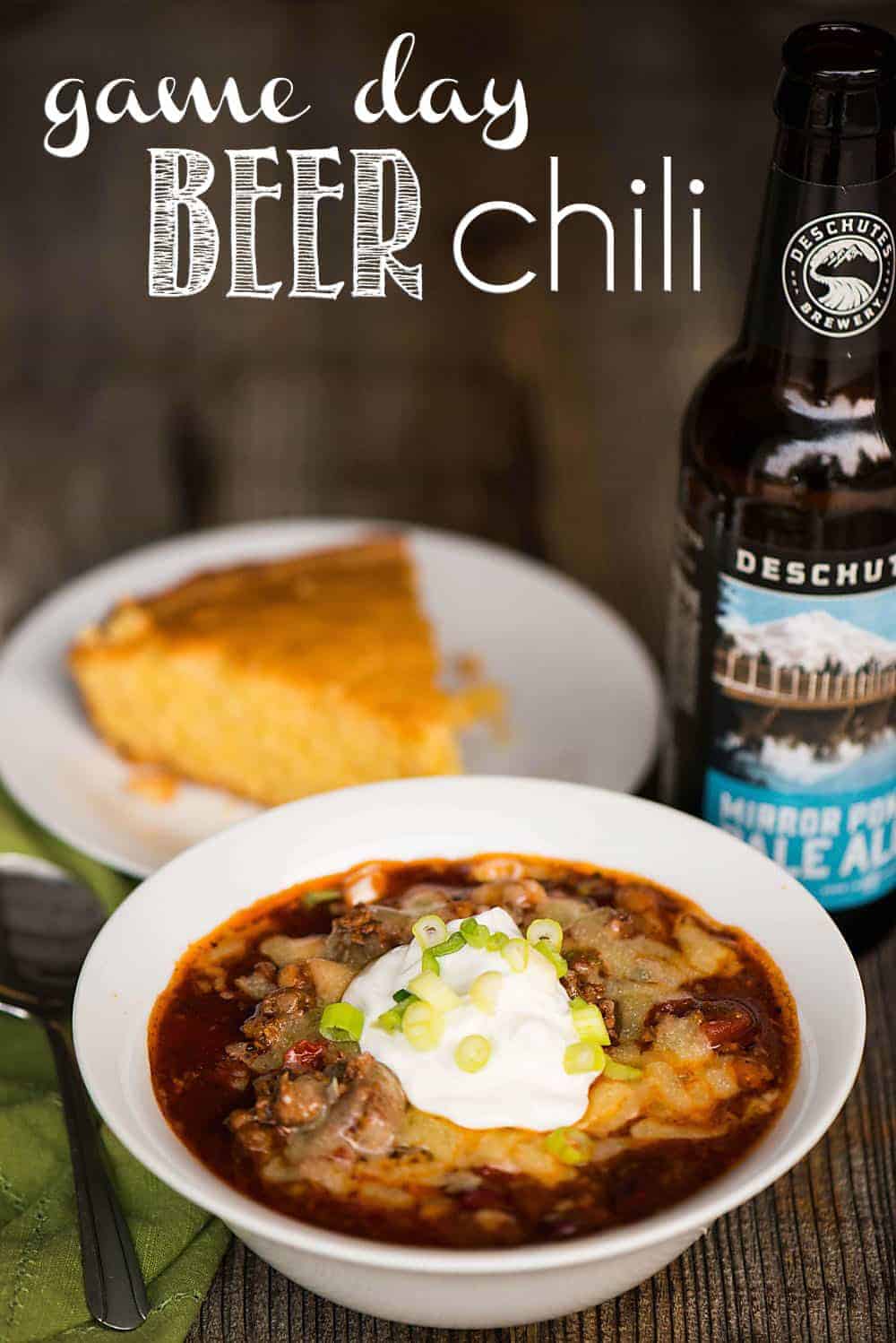 bowl of chili with a side of corn bread and a bottle of beer