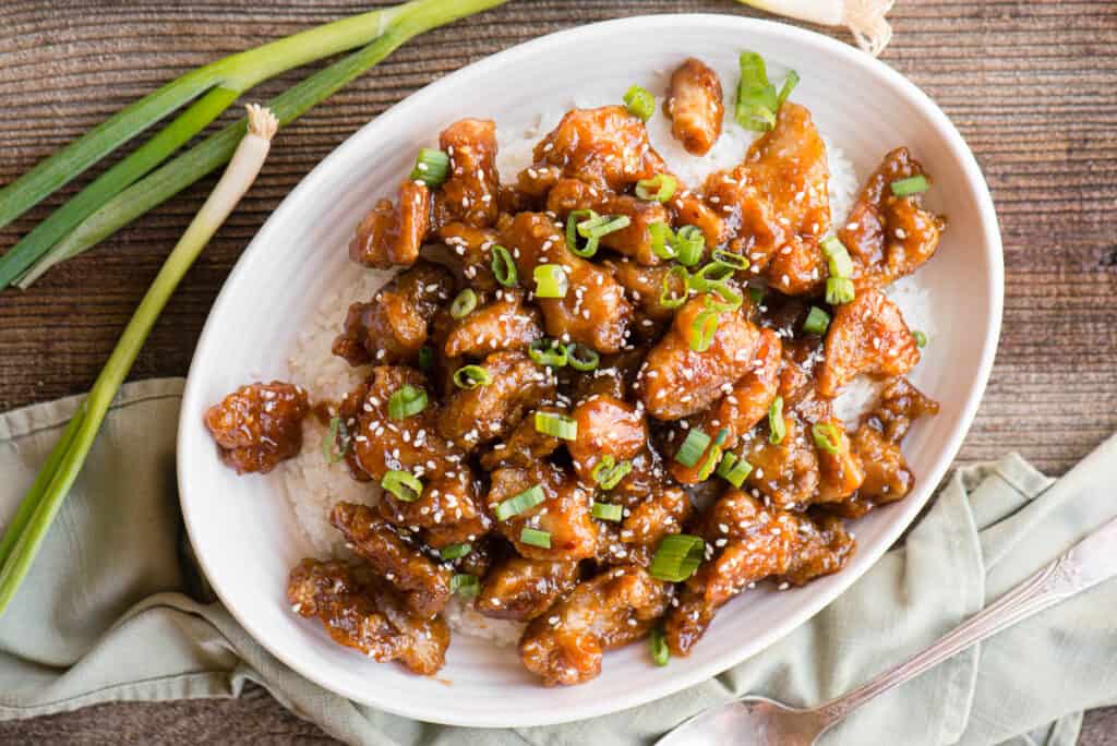 oval dish with General Tso's Chicken Recipe over rice with green onions
