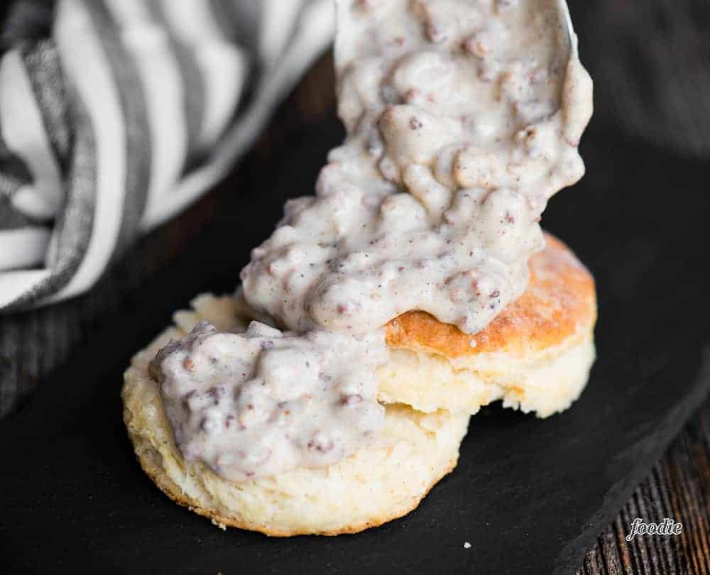 gluten free country sausage gravy getting spooned on top of a homemade biscuit