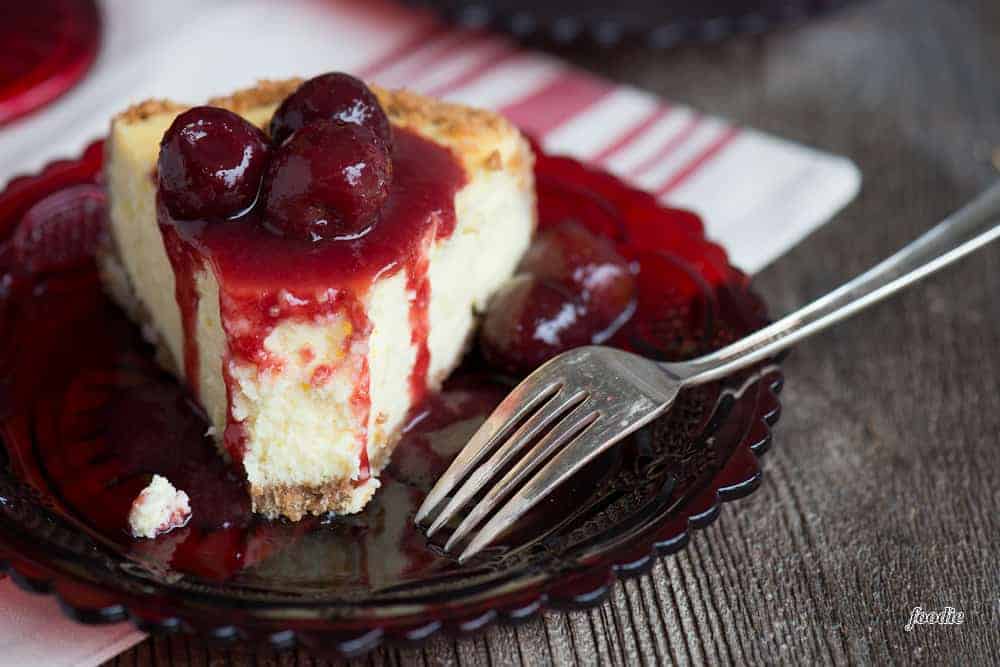 homemade cheesecake on plate with cherry topping