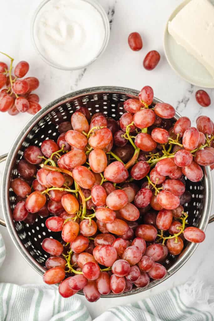 colander with bunch of red grapes