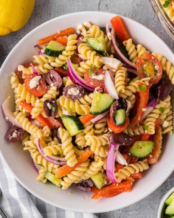 Greek pasta salad in white bowl.