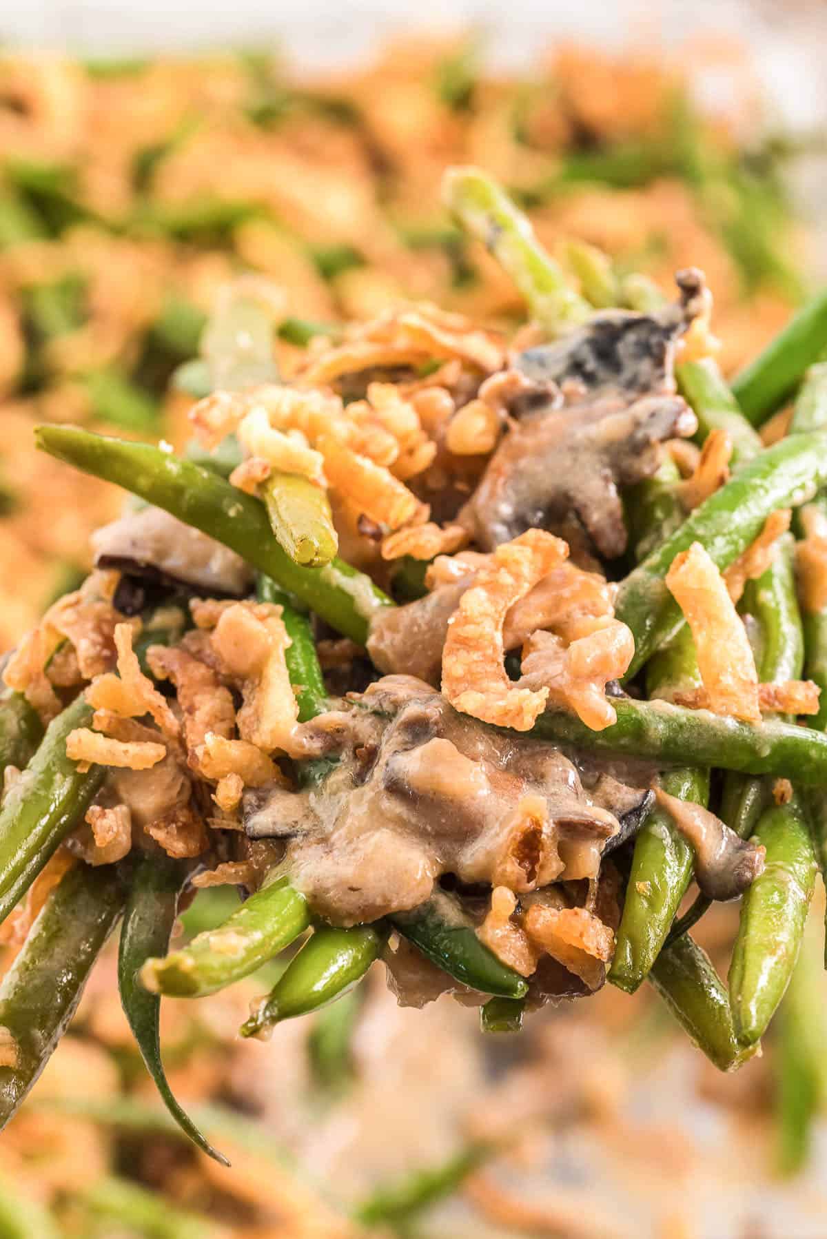 Scoop of homemade green bean casserole with crispy onion pieces.