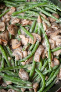 mixing fresh green beans with homemade mushroom gravy for green bean casserole recipe.