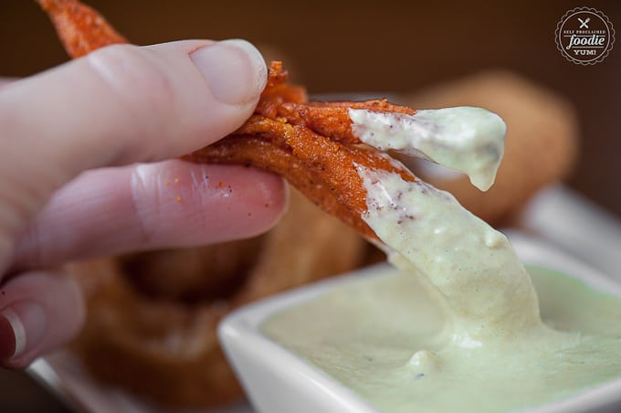 Sweet potato fry getting dipped in Green Chile Aioli