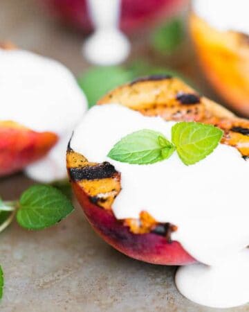 half of a grilled peach with sweetened cream on top