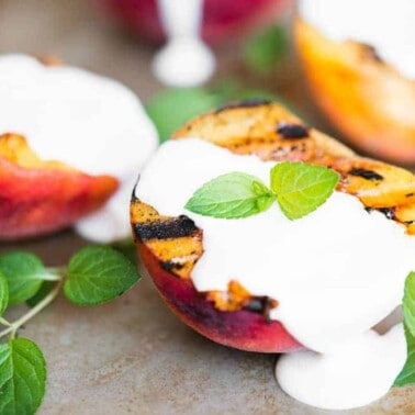 half of a grilled peach with sweetened cream on top