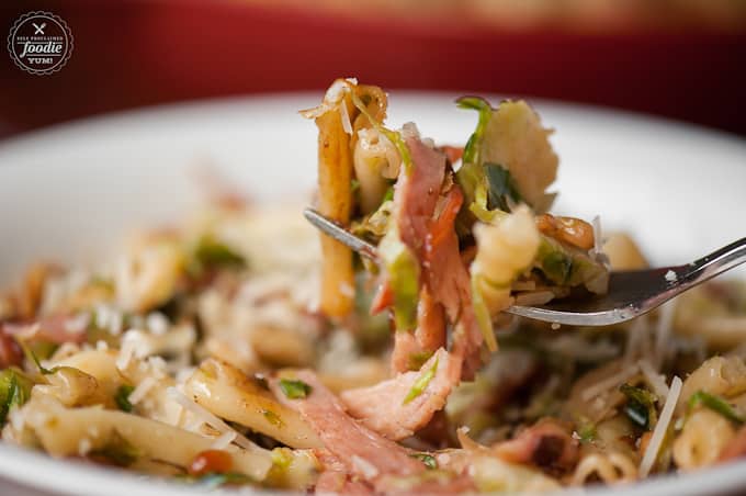 a fork with pasta, ham and brussels sprouts