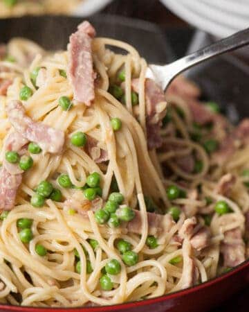 scooping homemade Pasta Carbonara with Ham and Pea out of pot