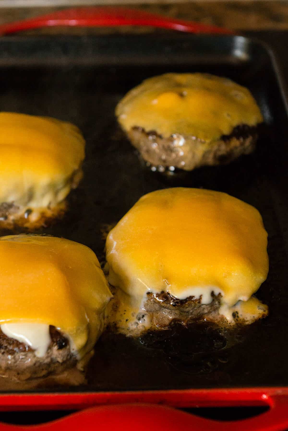 burger patties with melted cheese on griddle
