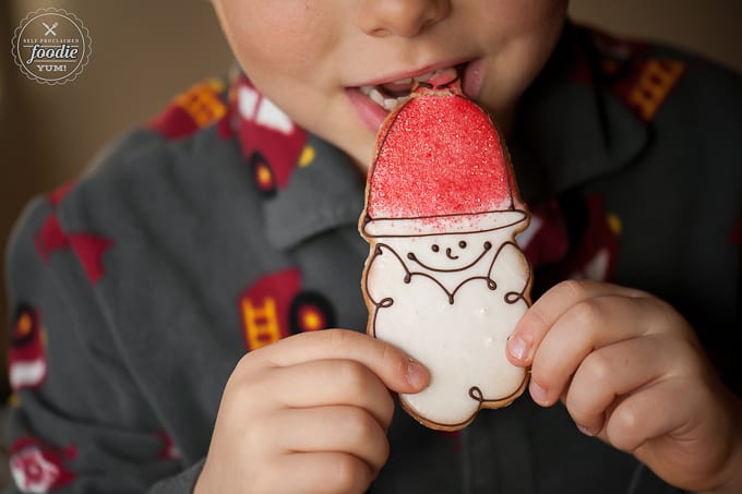 little boy eating santa decorated christmas sugar cookie