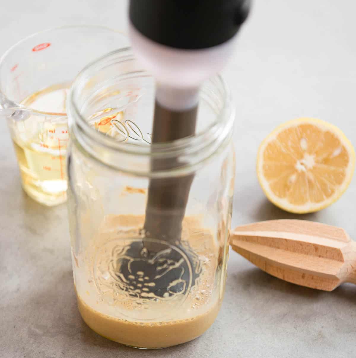 mixing homemade Caesar Salad Dressing with immersion blender