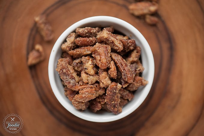 A close up of a bowl of candied pecans on a plate