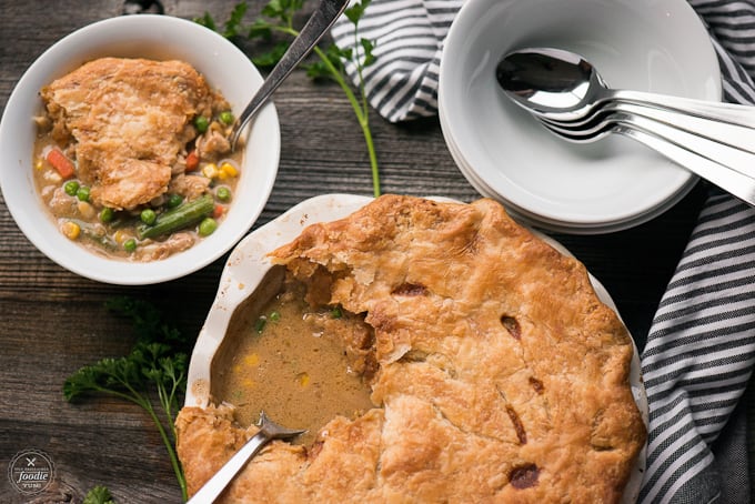 wooden table with chicken pot pie and white bowls