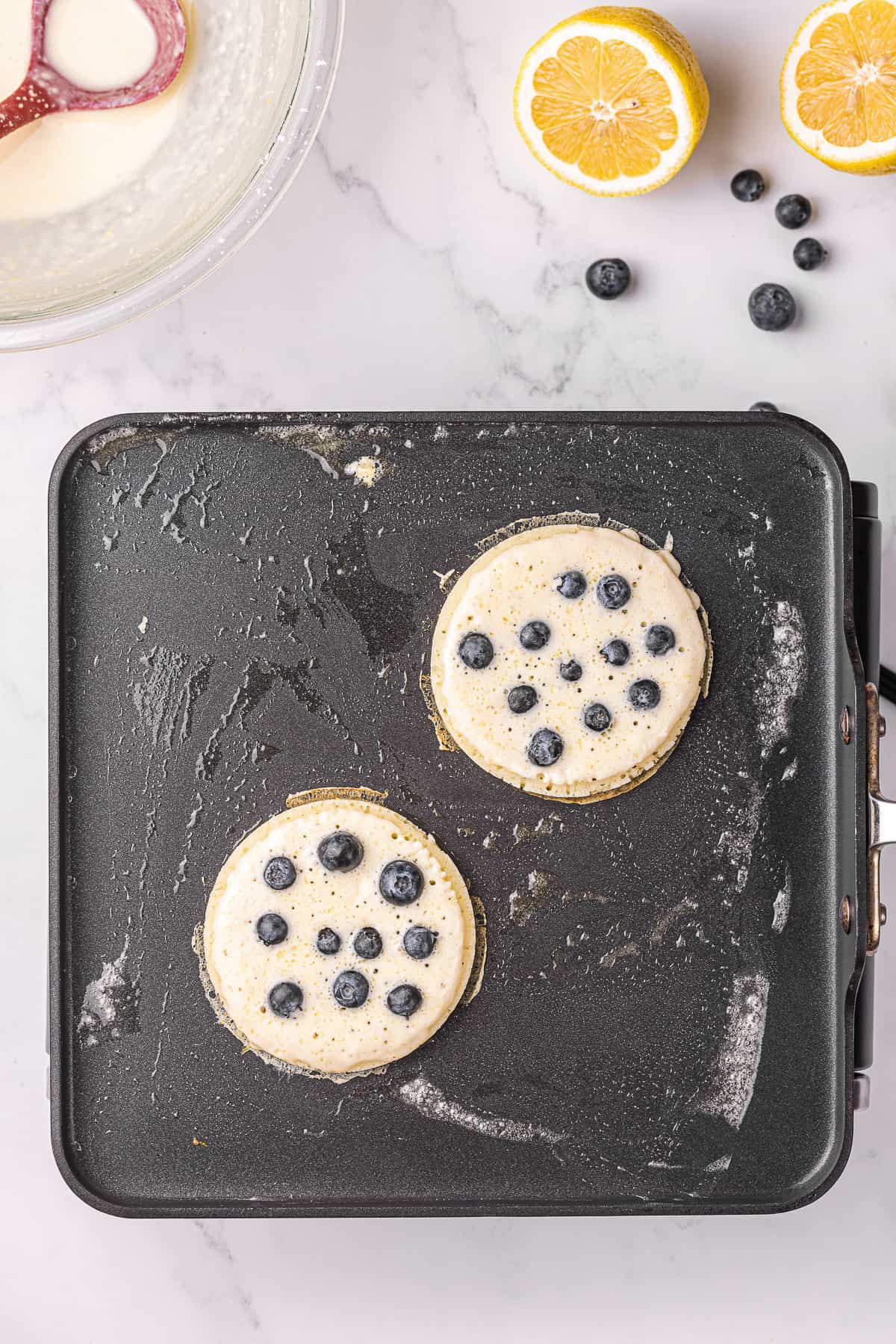 lemon blueberry pancakes on griddle before they get flipped.