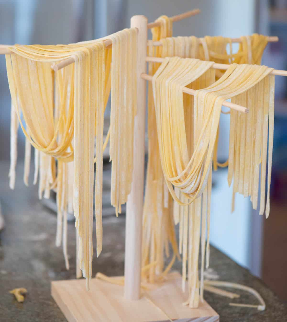 homemade pasta noodles hanging on drying rack.