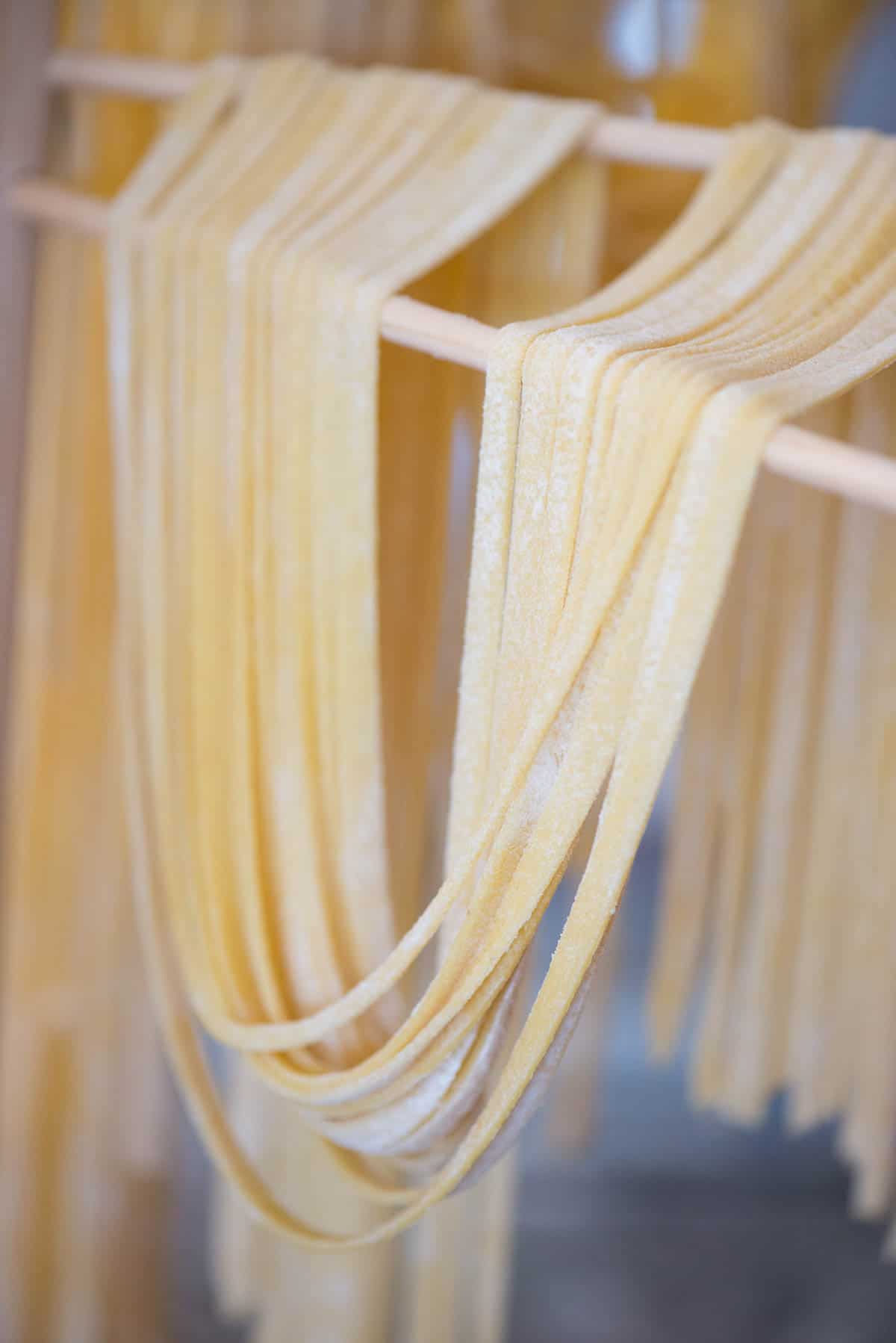 long homemade noodles on wooden drying rack.