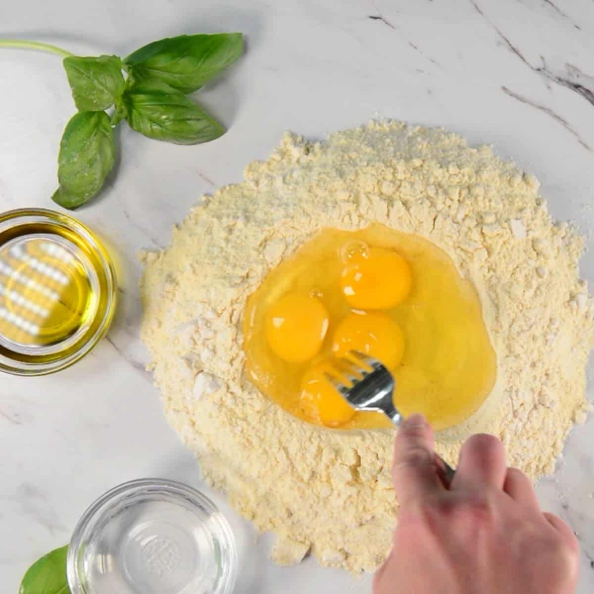adding eggs to flour mixture for homemade pasta recipe.