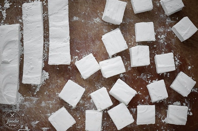 cut squares of peppermint marshmallows on brown cutting board