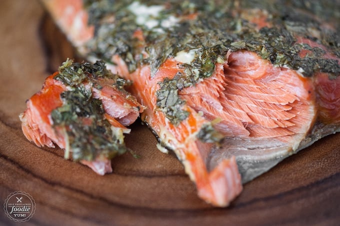 A close up of a slice of hot smoked salmon with herbs