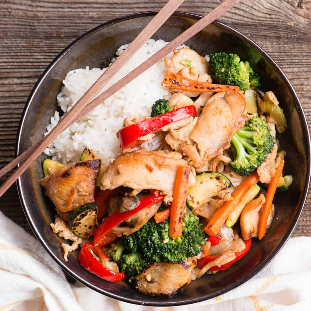 chicken and vegetable stir fry in bowl with rice