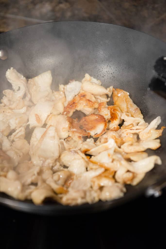 thin sliced chicken breast in wok pan