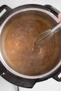stirring onion gravy with whisk