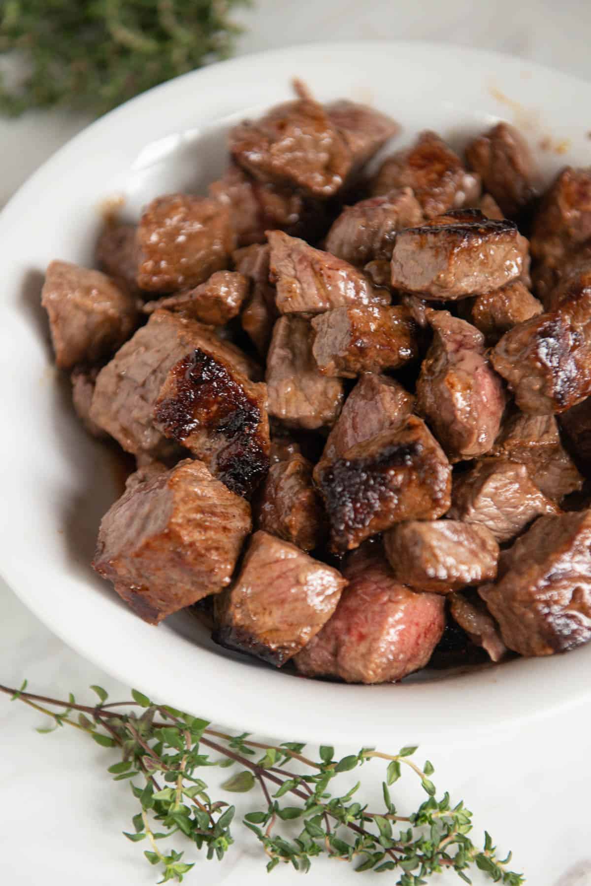 seared stew meat in white bowl.