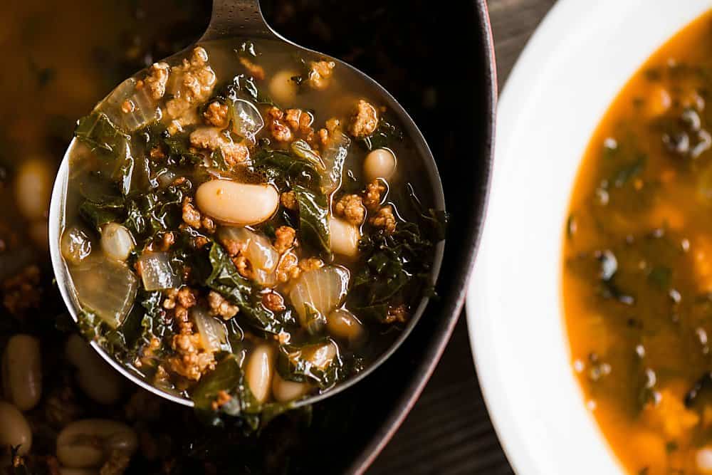 ladle of soup with sausage and beans