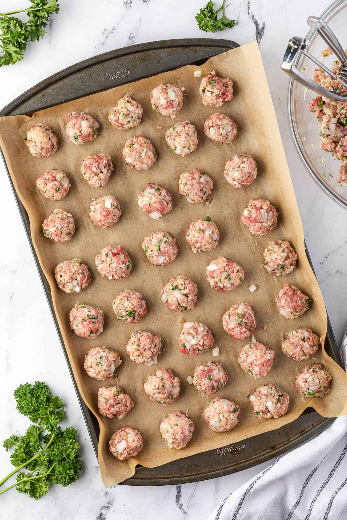 uncooked meatballs on parchment lined pan.