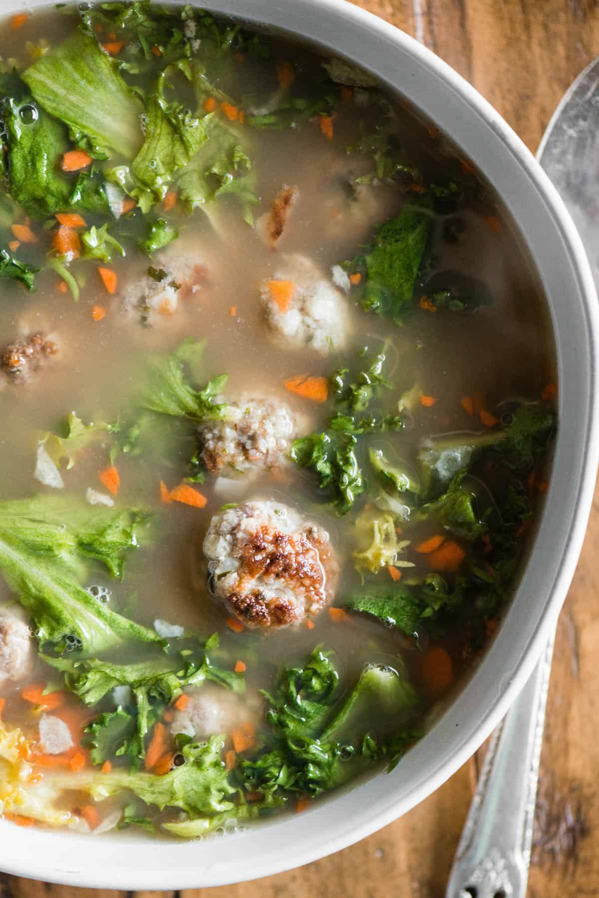 Top view of Italian wedding soup made with meatballs and endive.