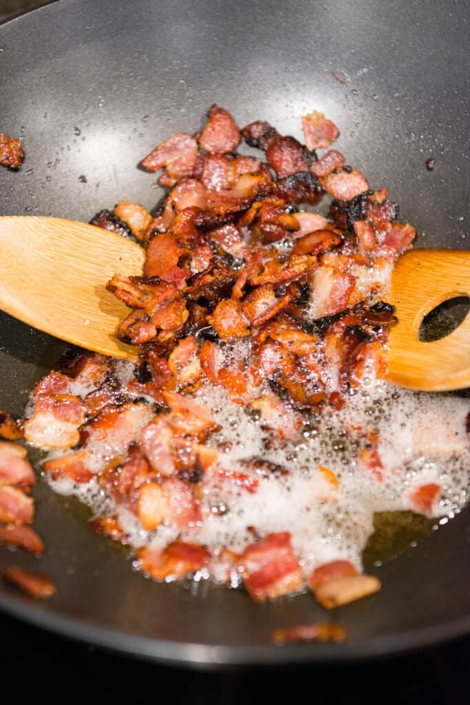 cooking bacon pieces in wok pan