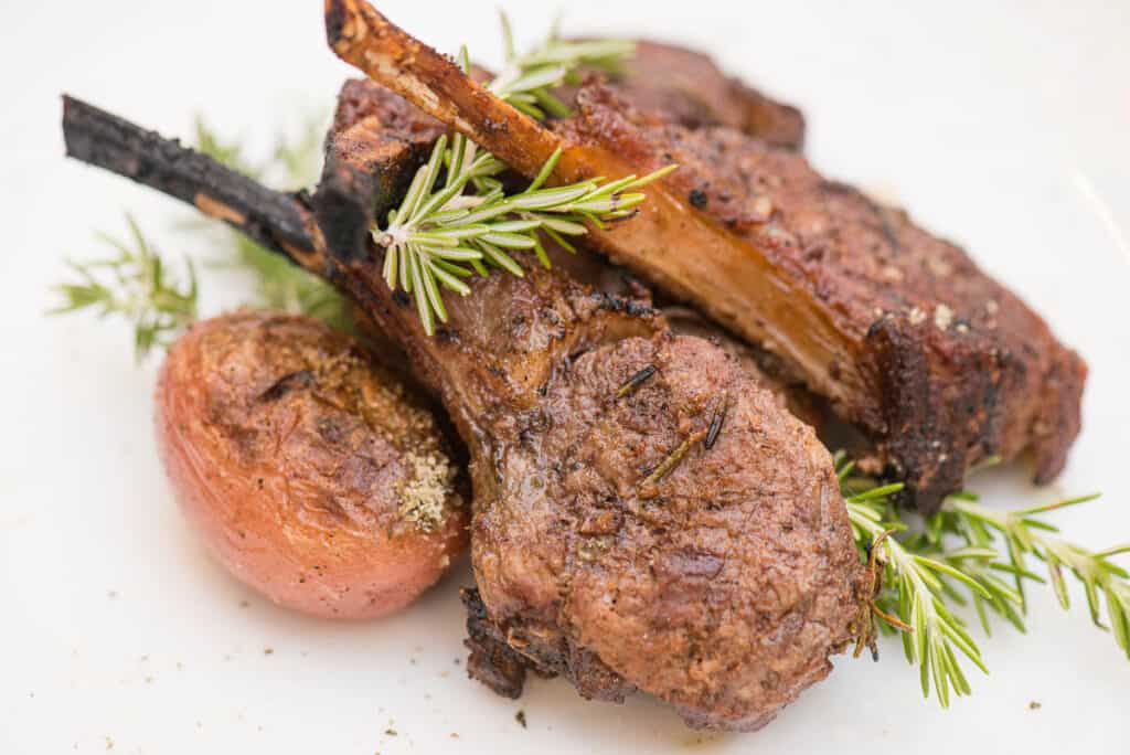 close up of grilled lamb chops with potato and rosemary