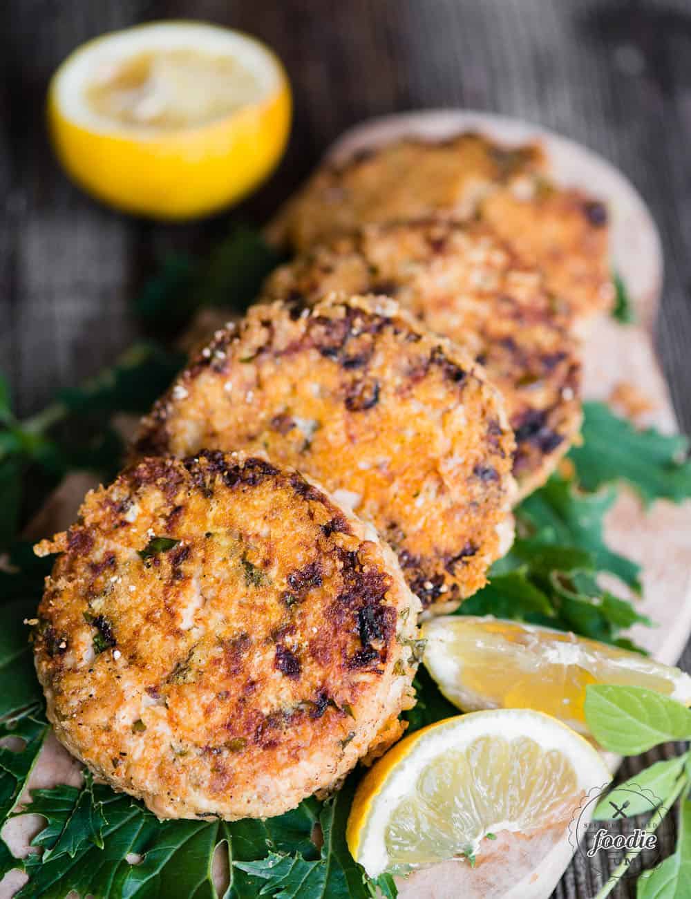 golden brown lemon basil salmon patties with lemon and lemon basil garnish