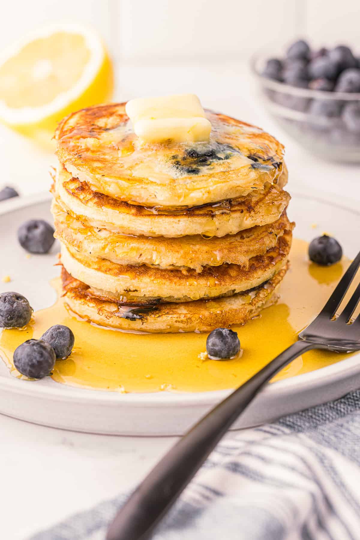 lemon blueberry pancakes on plate with syrup and butter.