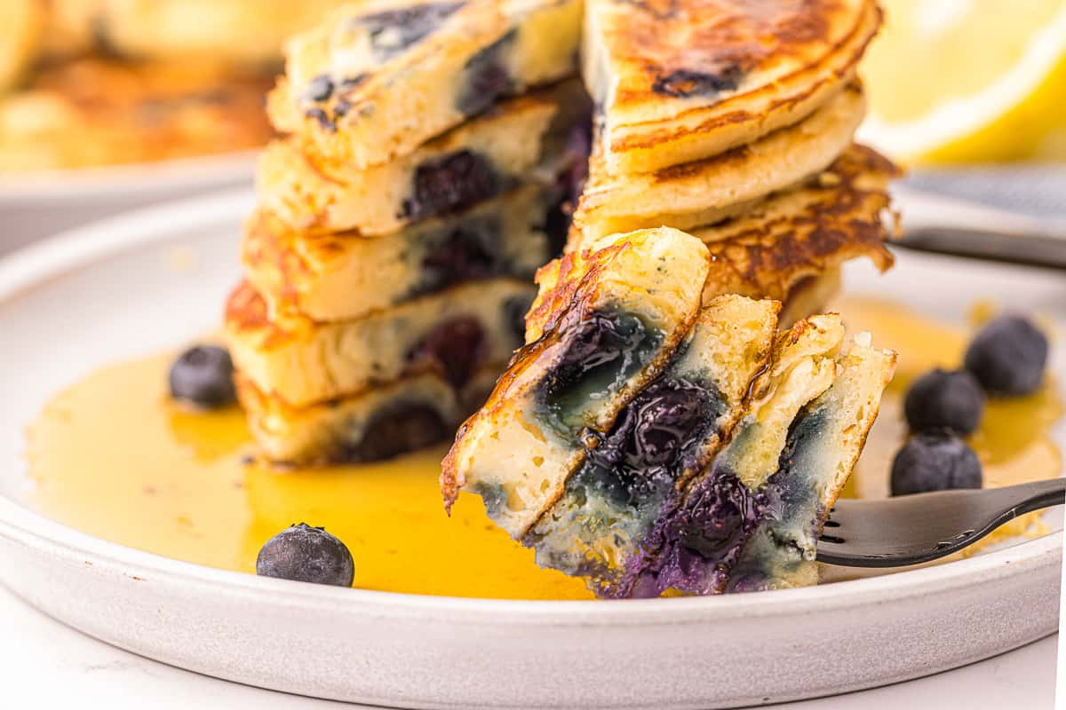 bite of homemade lemon blueberry pancakes with pieces on fork.