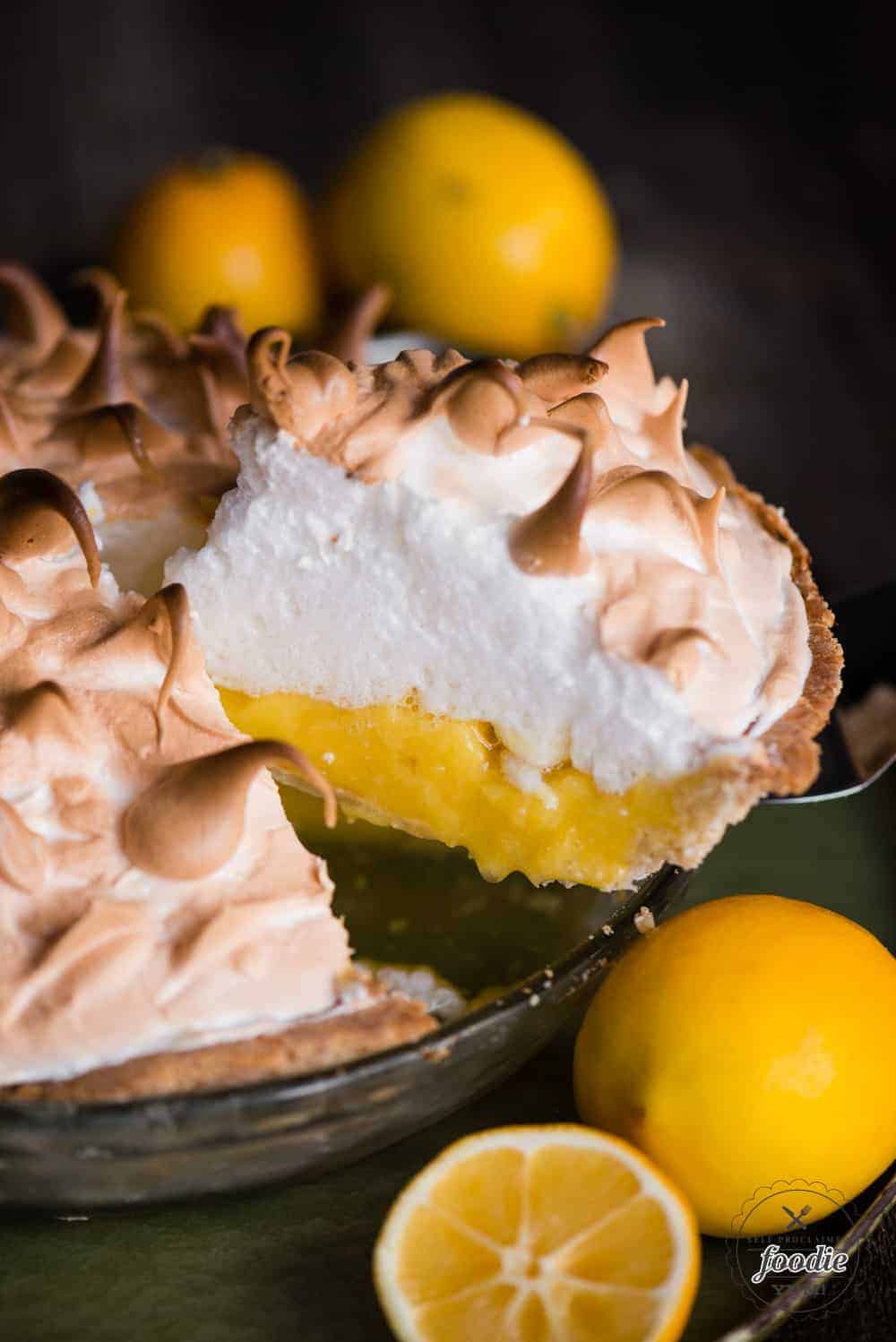 using a pie server to pull a piece of lemon pie out of dish