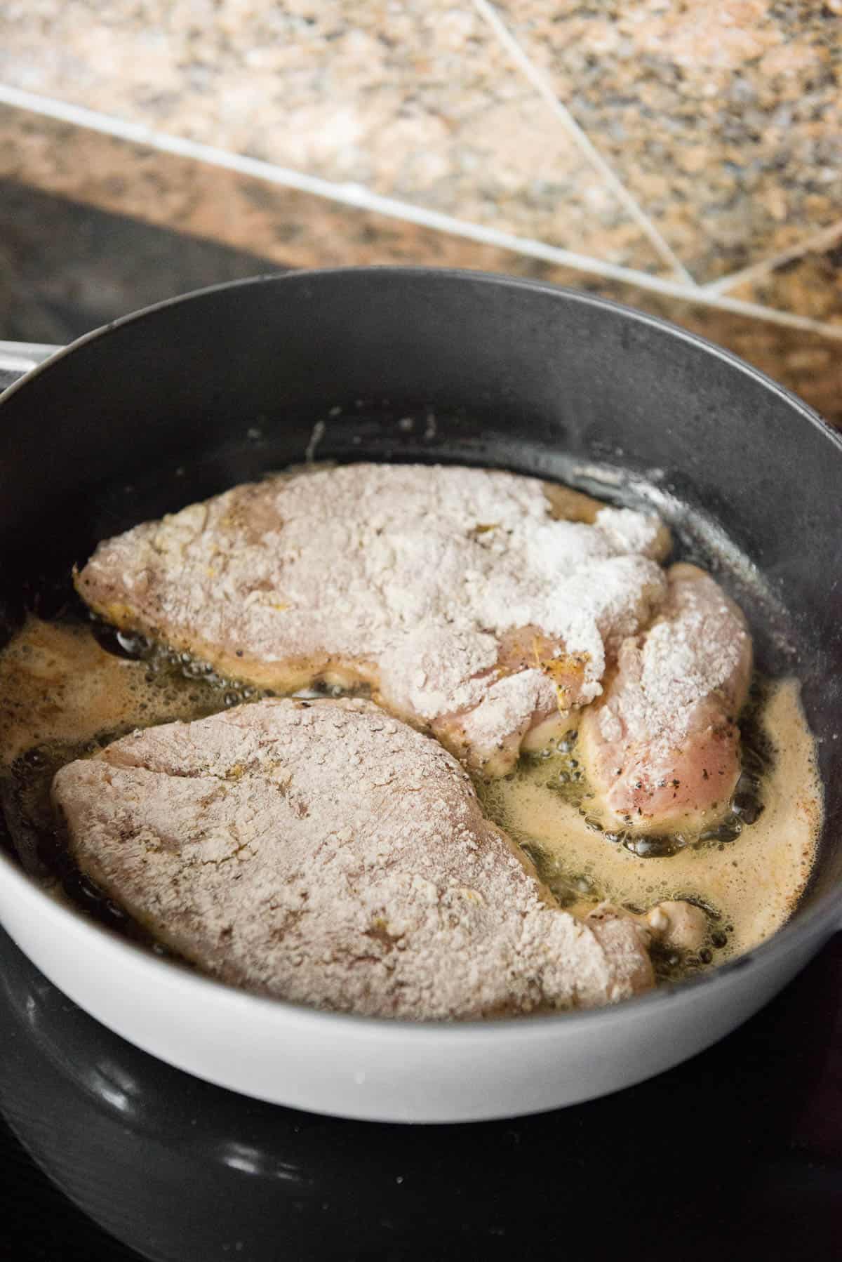 flour coated chicken breast in pan