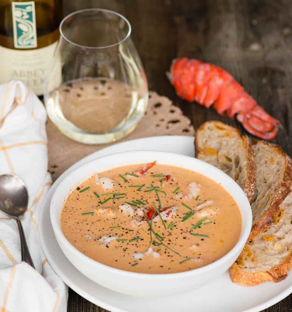 homemade lobster bisque with glass of wine and bread on side