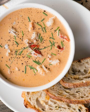 homemade lobster bisque in bowl with bread on side