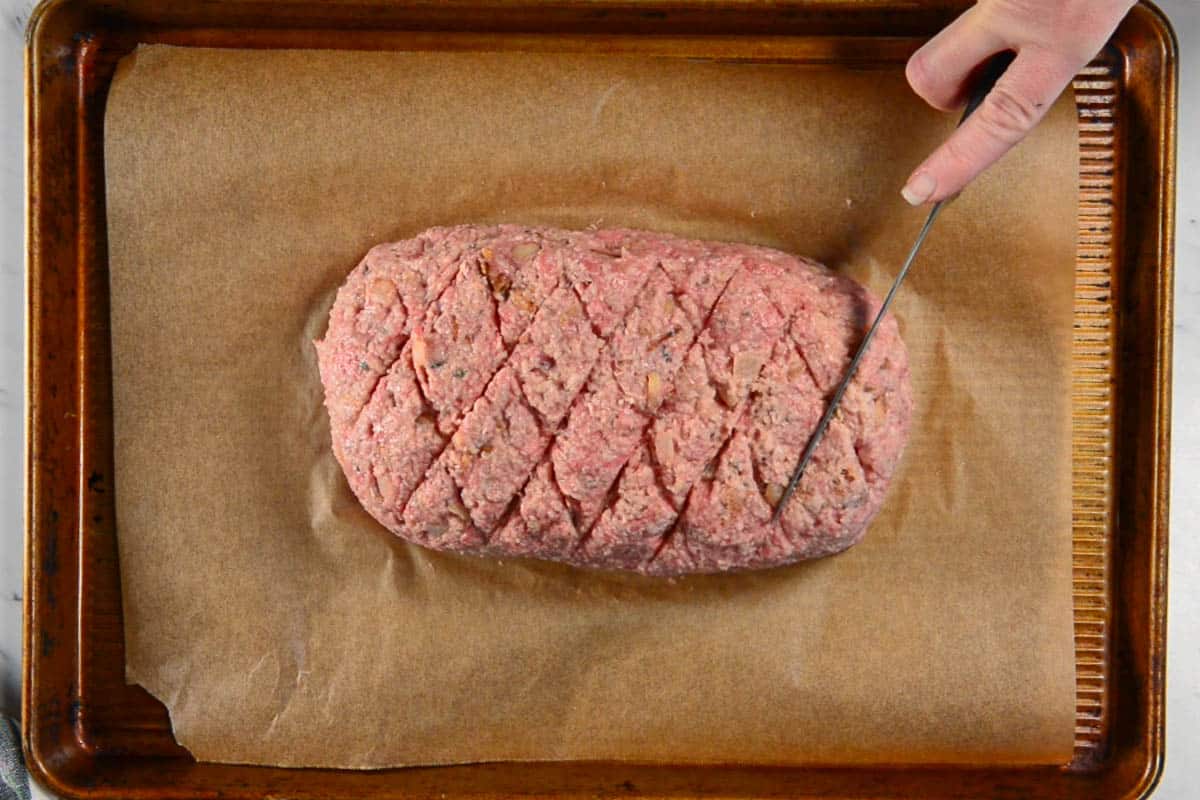cutting a diamond pattern into a meatloaf that will be baked in oven.