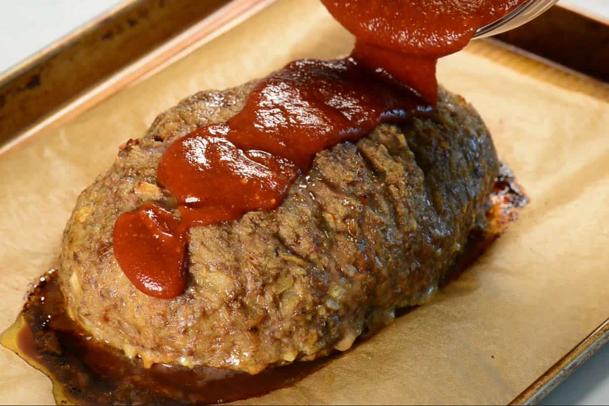 pouring sauce over meatloaf.