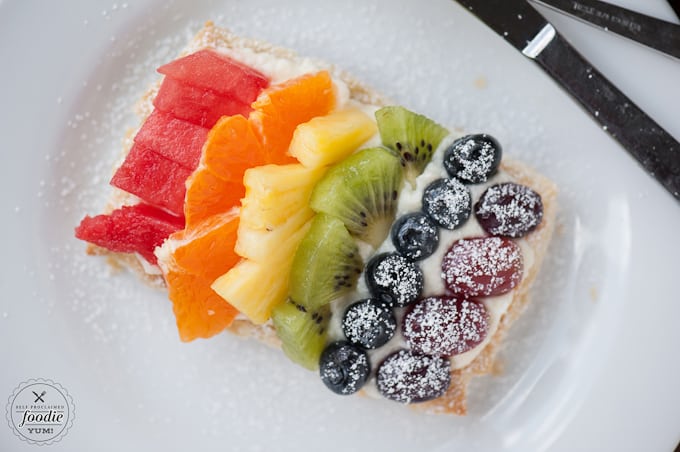 a rainbow of fruit on top of puffed pastry and cream