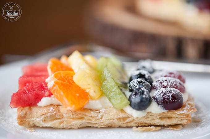 A close up of puff pastry topped with a creamy filling and fresh fruit