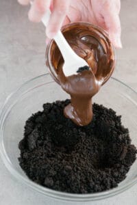 adding melted chocolate to crushed oreos