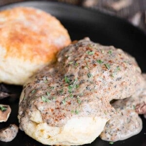 black plate with two homemade buttermilk biscuits topped with vegetarian country mushroom gravy