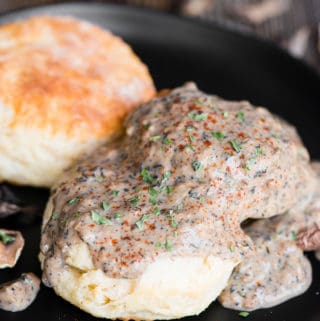 black plate with two homemade buttermilk biscuits topped with vegetarian country mushroom gravy