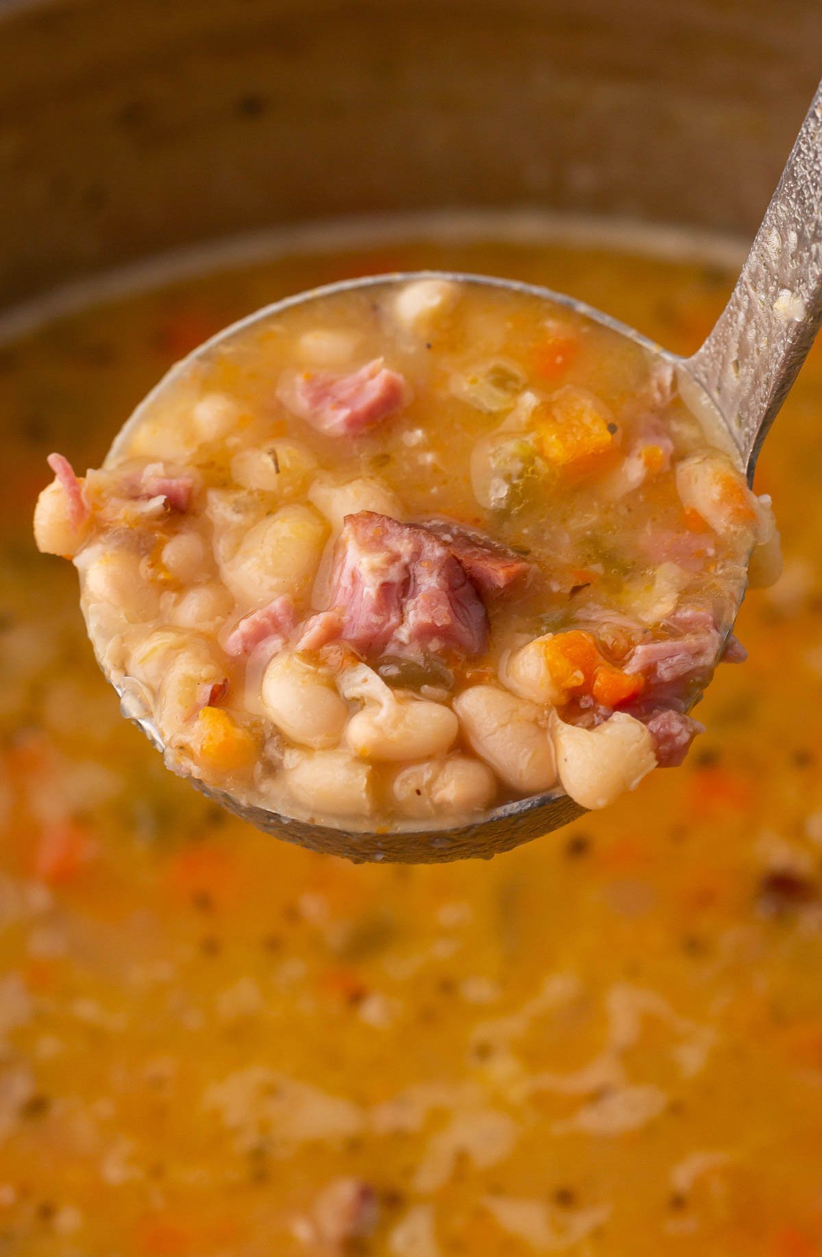 ladle of homemade navy bean soup with ham.