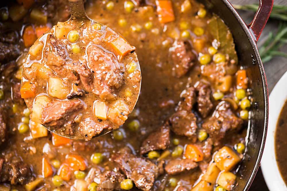 ladle of beef stew over pot